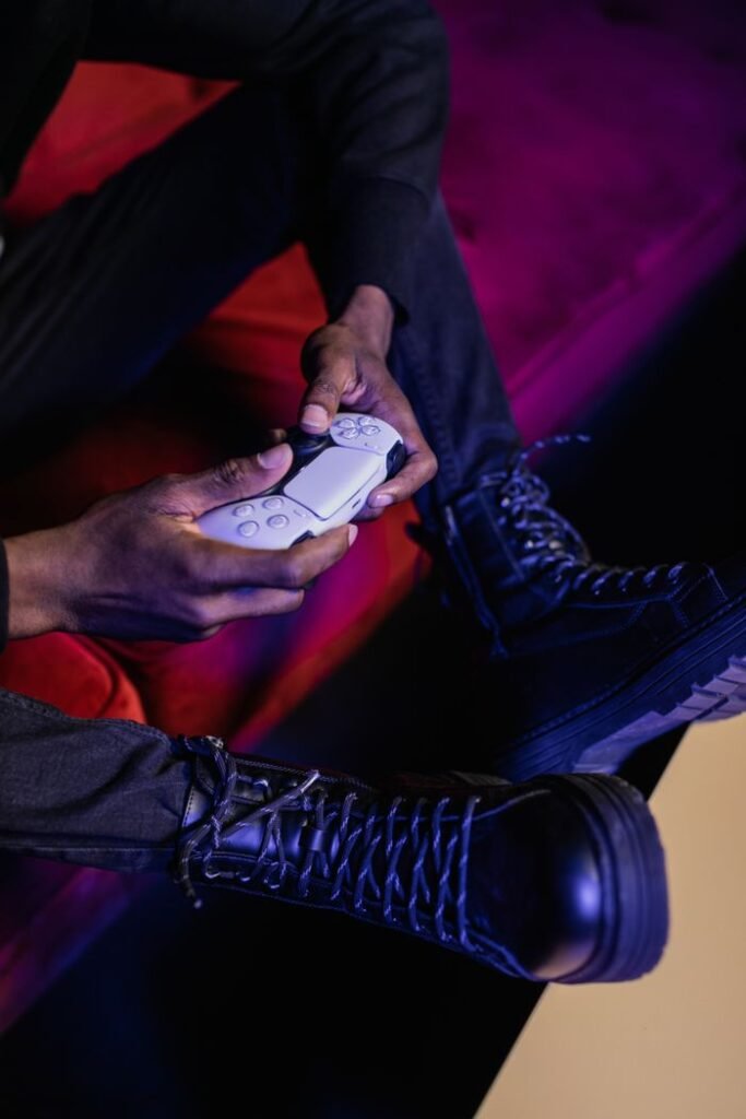Person holding a game controller, wearing leather boots. Perfect stock photo for gaming and lifestyle content.